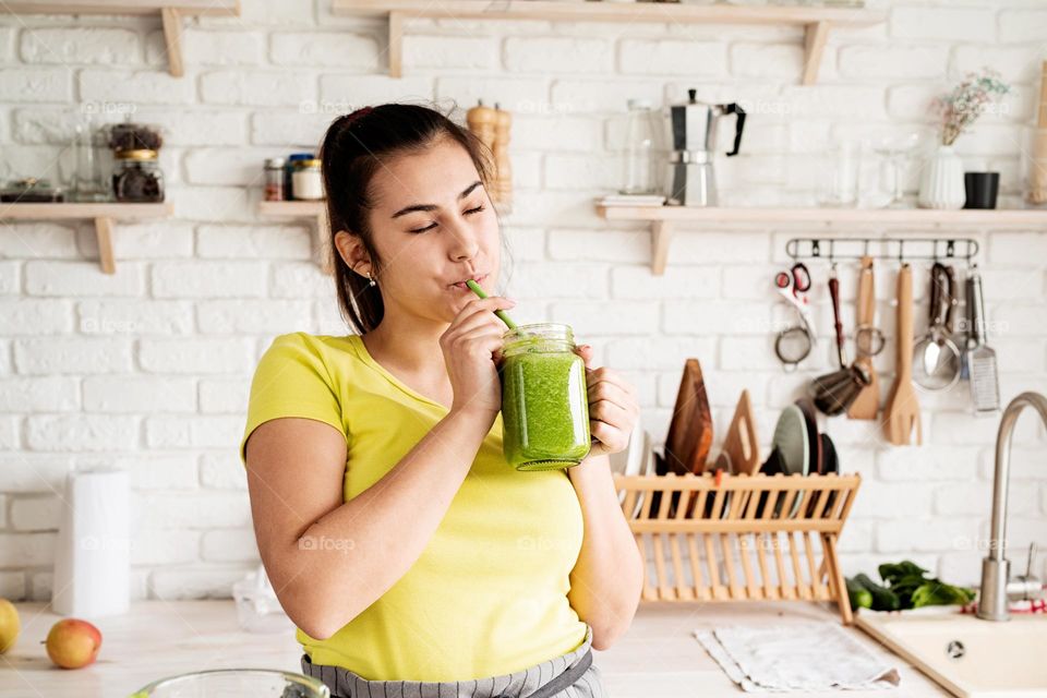 woman drinking smoothie in the kitchen