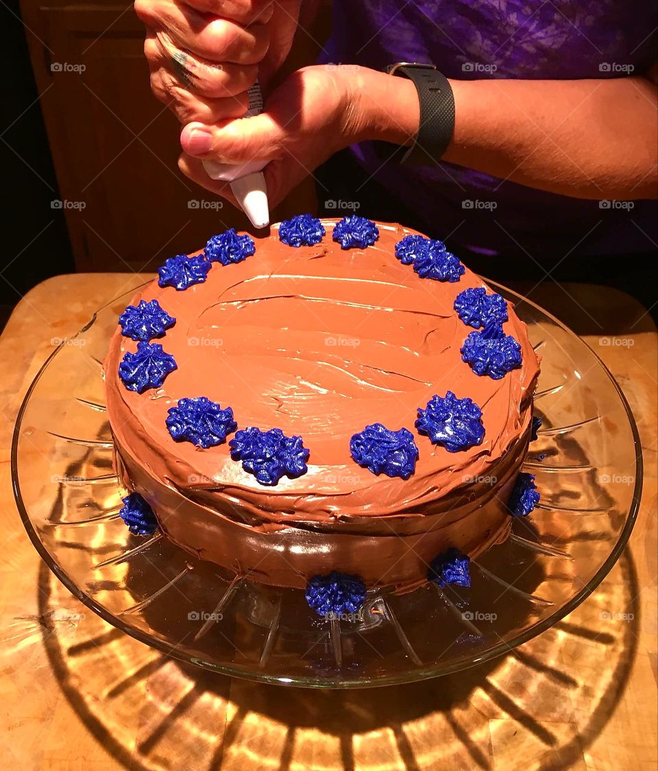 Decorating chocolate cake on pedestal cake dish.