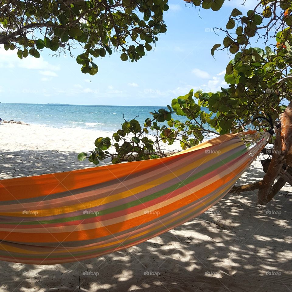 A striped hammock beckons on a lazy afternoon at the beach.