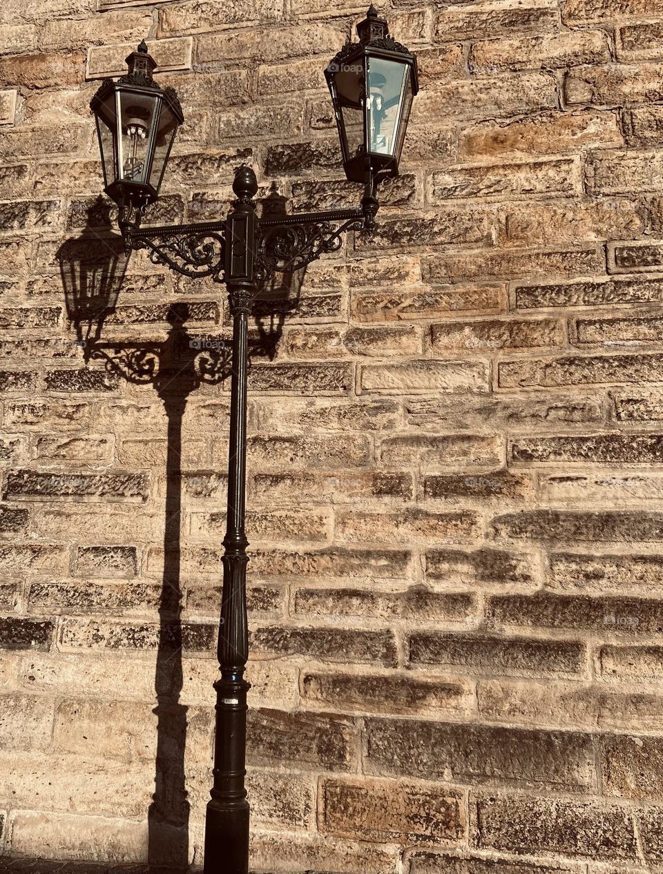 Vintage street lamps against a brick wall.