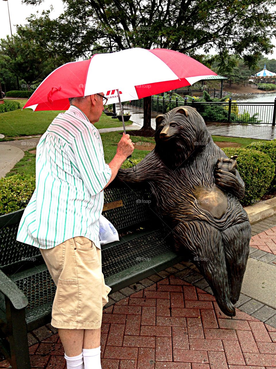 Man and Bear. Man talking to bear sculpture in park on a rainy day