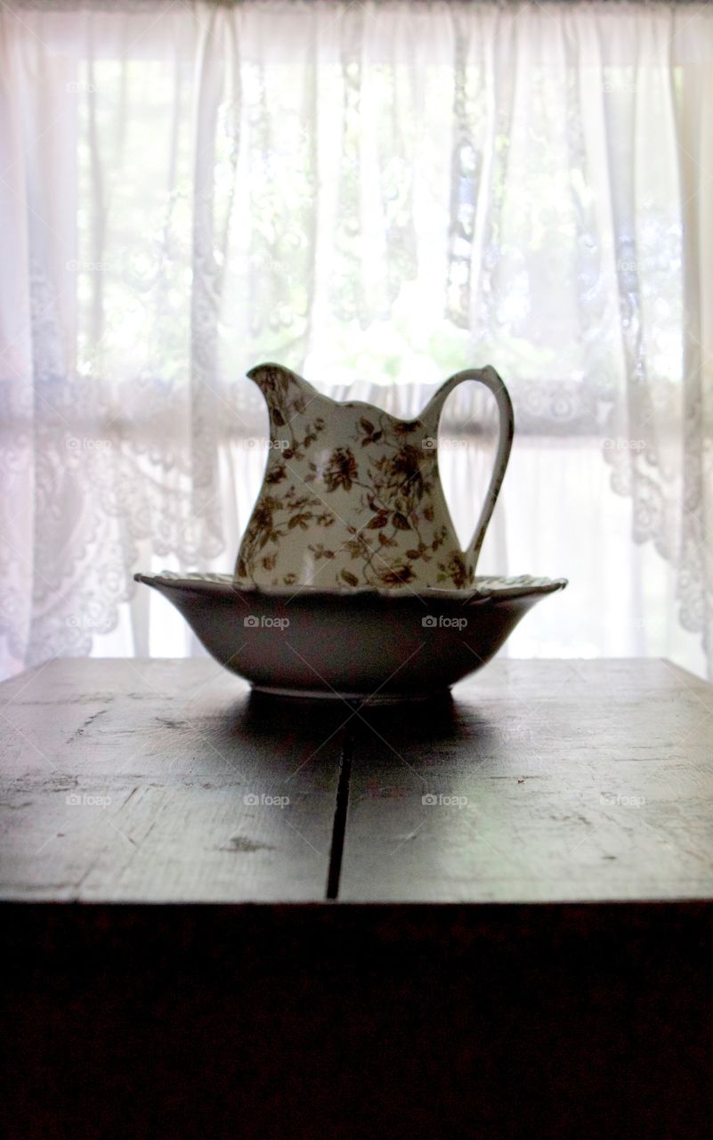 Minimalistic Snaps - backlit pitcher and basin on a wooden surface 