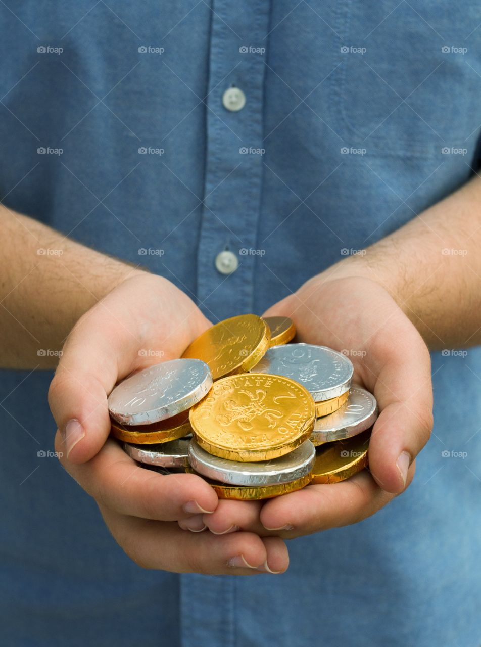 A man holding a handful of gold and silver coins.
