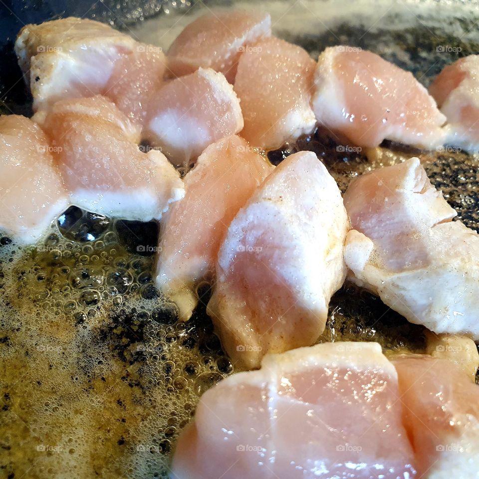 Chicken that is fried in a pan