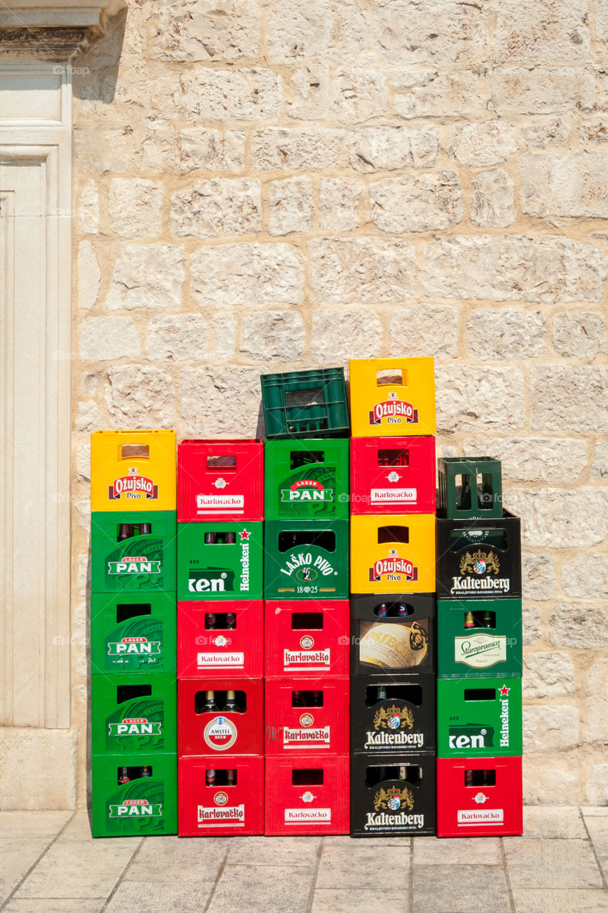 Colorful beer containers stacked against masonry wall.