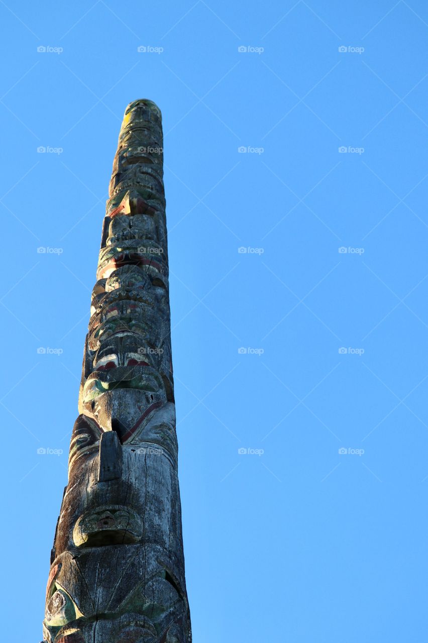 Coast Salish Indian carved wood Totem Pole (Vancouver BC Canada) against a vivid blue sky 