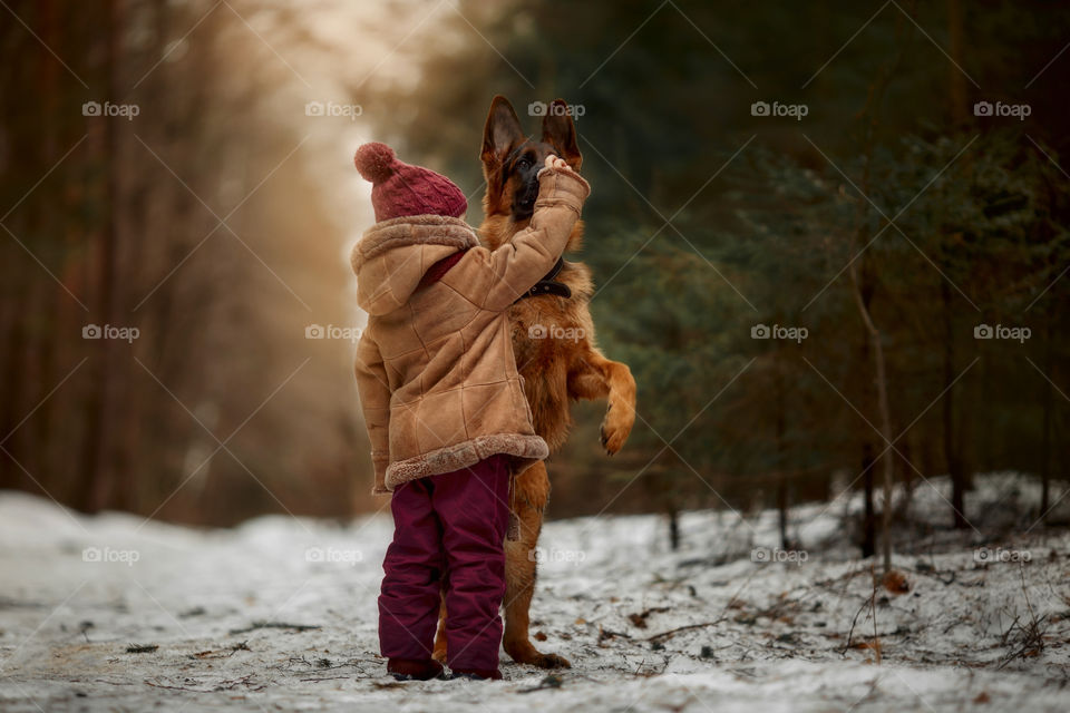 Little girl with German shepherd 6-th months puppy at early spring forest