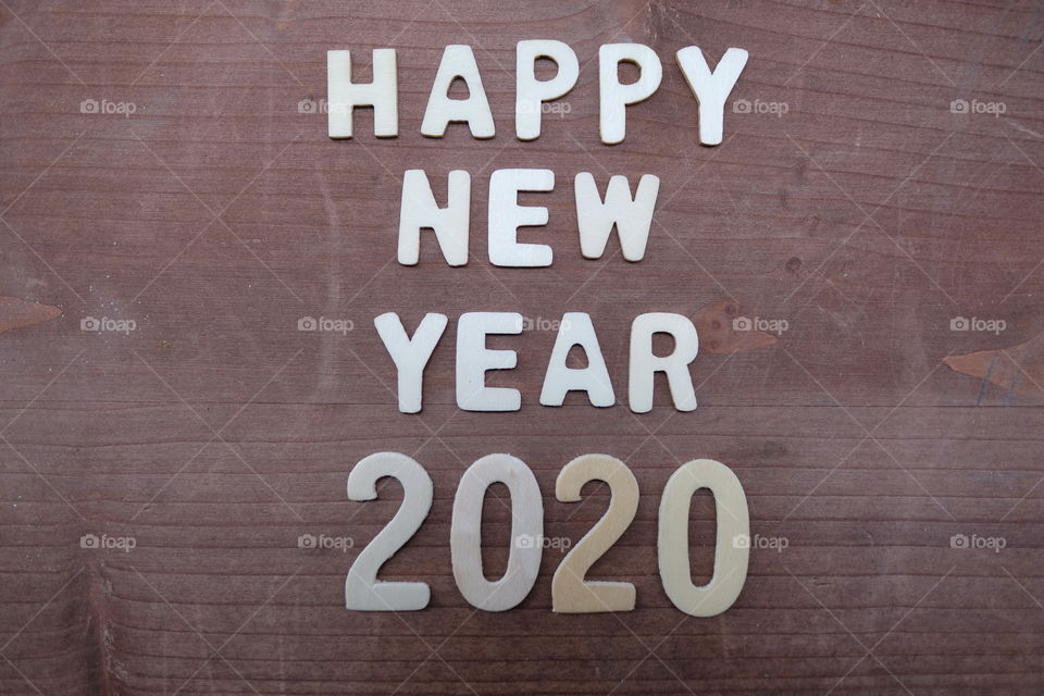 Happy New Year 2020 composed with wooden letters and numbers over a wooden board