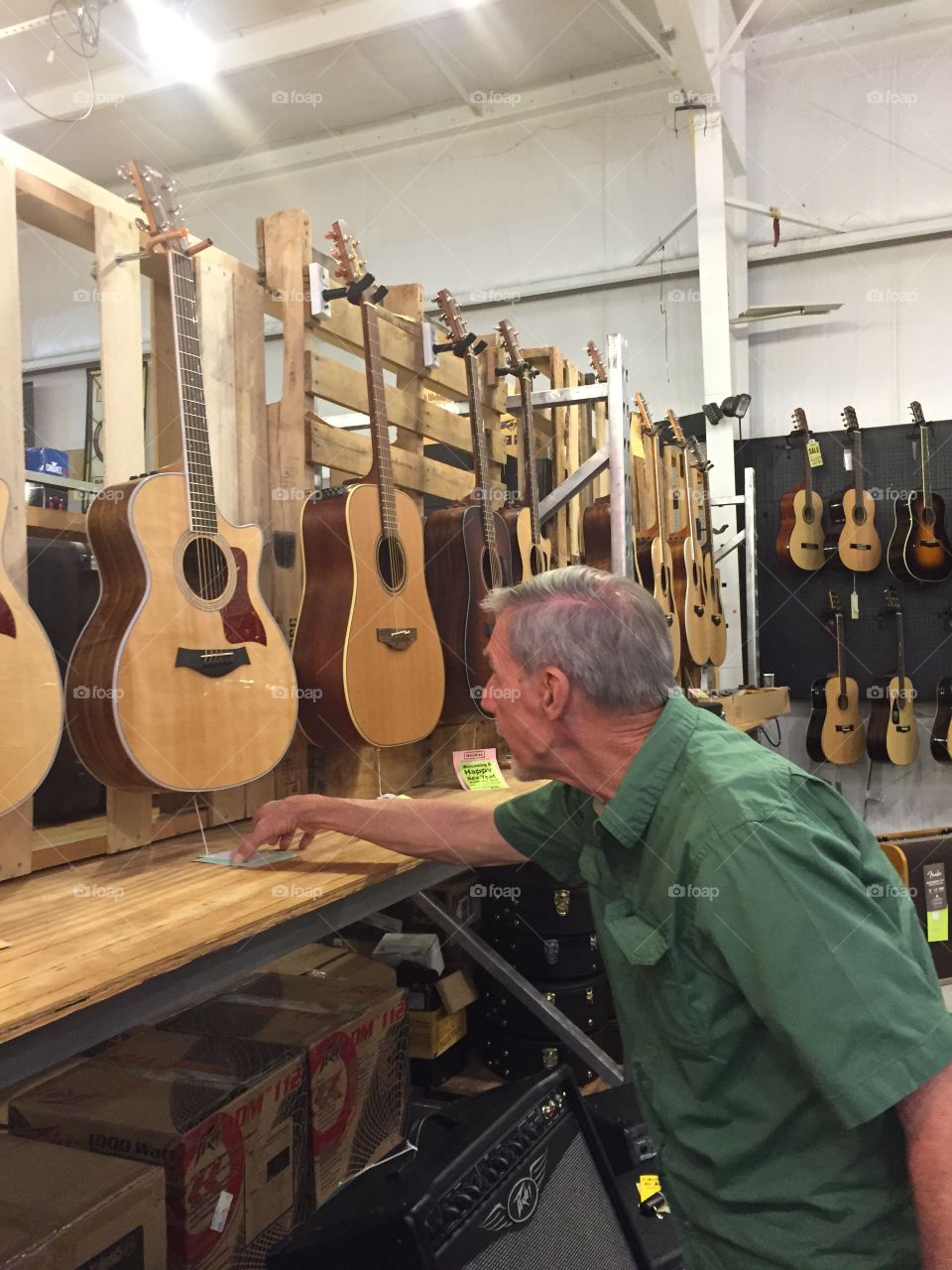 Man looking at Taylor guitars in a guitar shop.