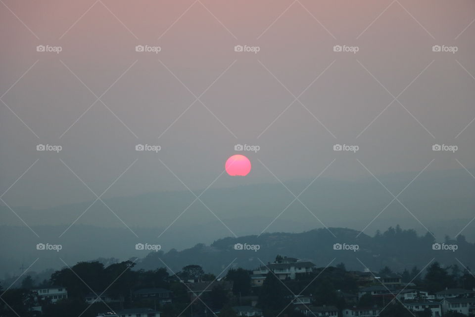 Pink sun settling in a smoky sky