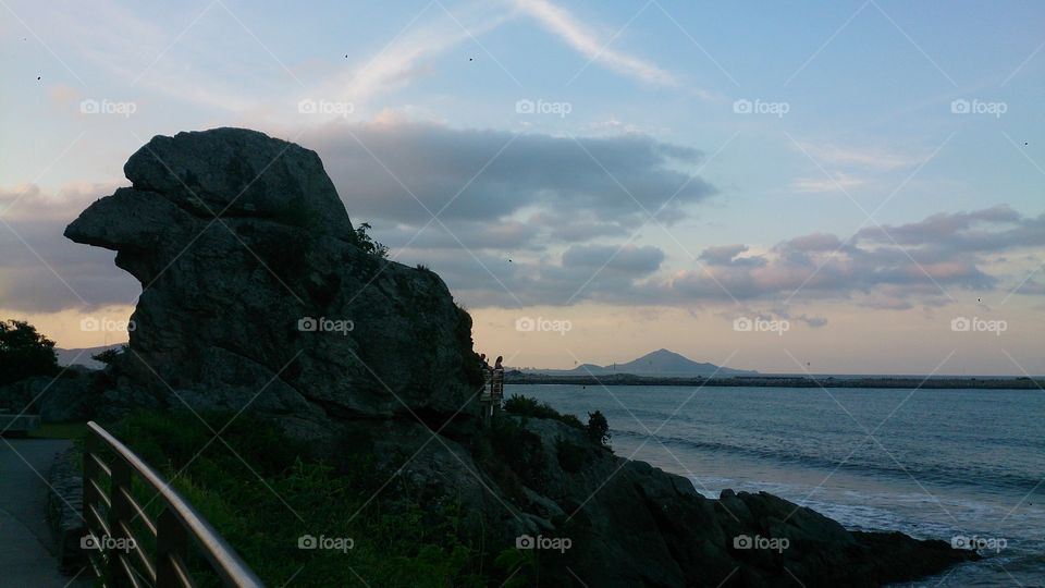 Evening view of the ocean.  Mountains, rocks, horizon, waves and surf, blue skies.
