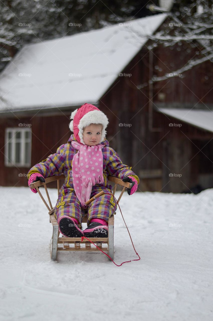 little girl siting  on the sledge