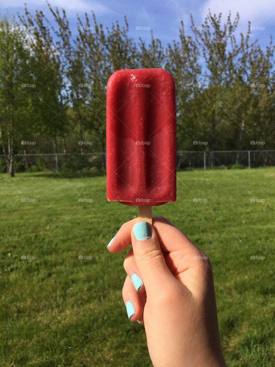 Holding a red popsicle on beautiful weather day
