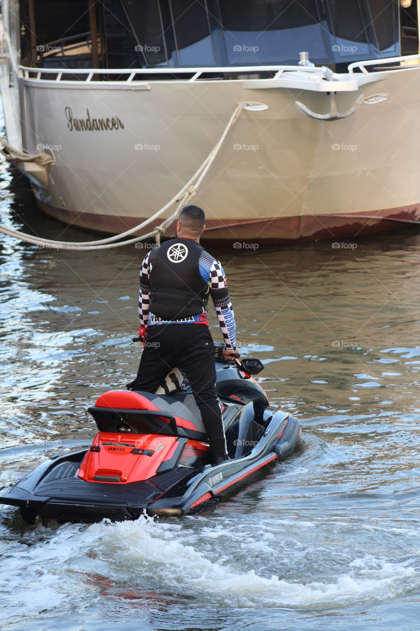 Man standing on jet ski near boat on Hudson River 