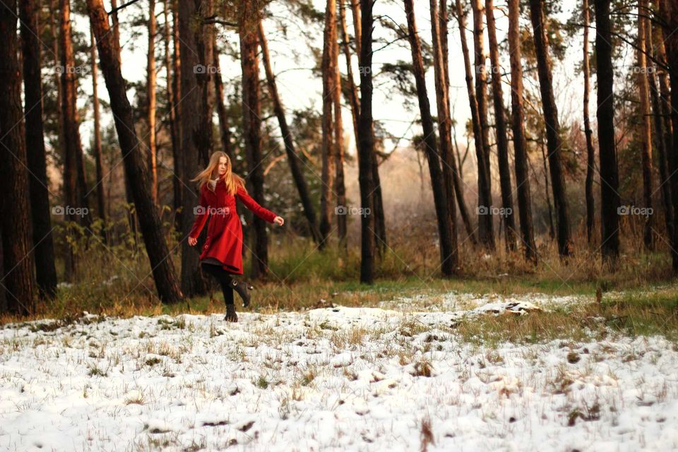 Girl dancing in a red coat in the spring forest