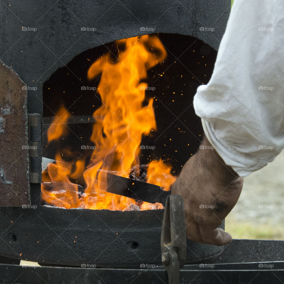 Blacksmith heating steel in a fire