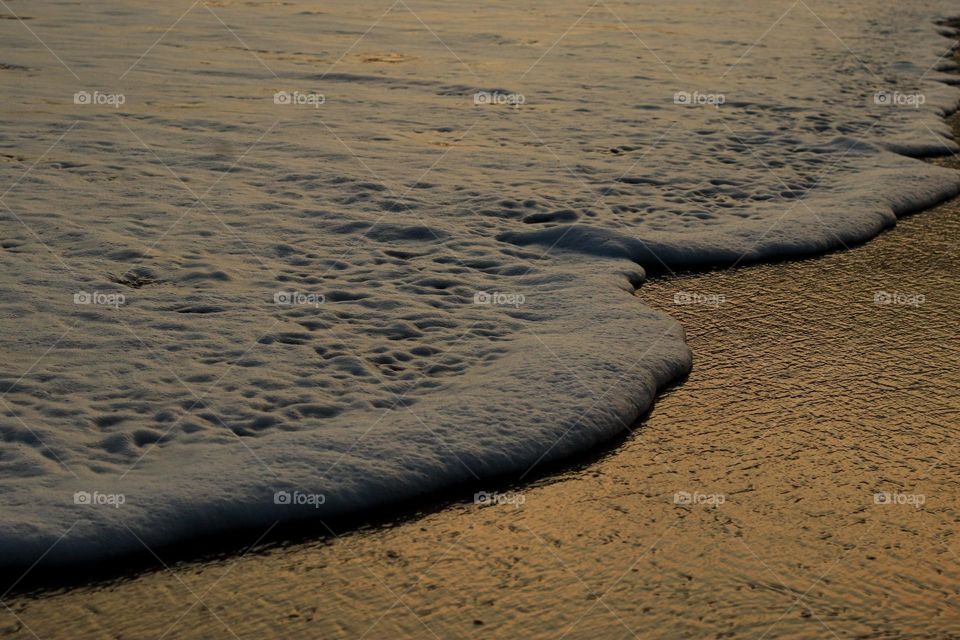 ondas em praia no horário do por do sol.