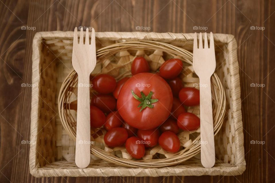 Wooden forks, plate and dish.  Ripe tomatoes in a wooden bowl