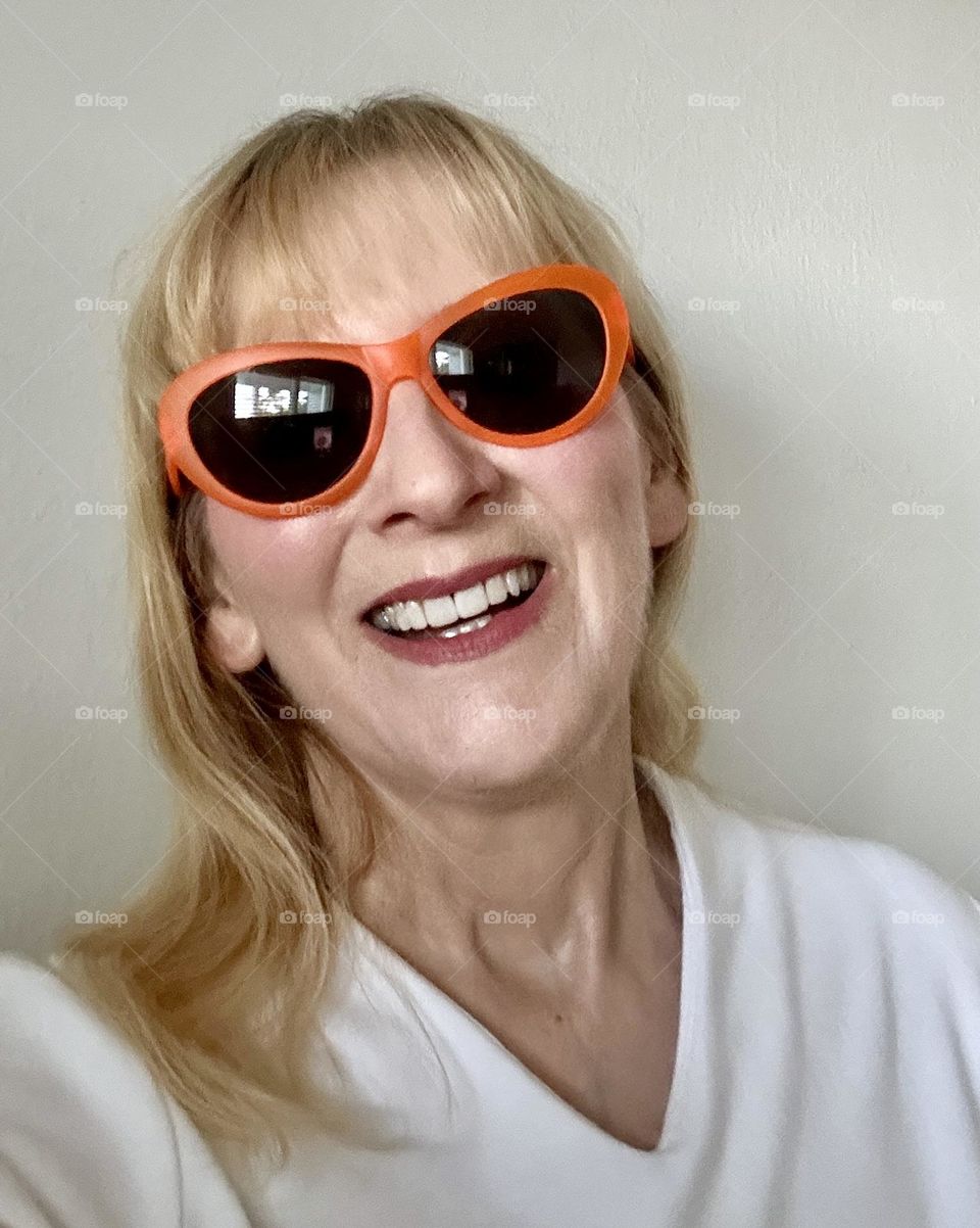 Woman smiling wearing orange sunglasses 