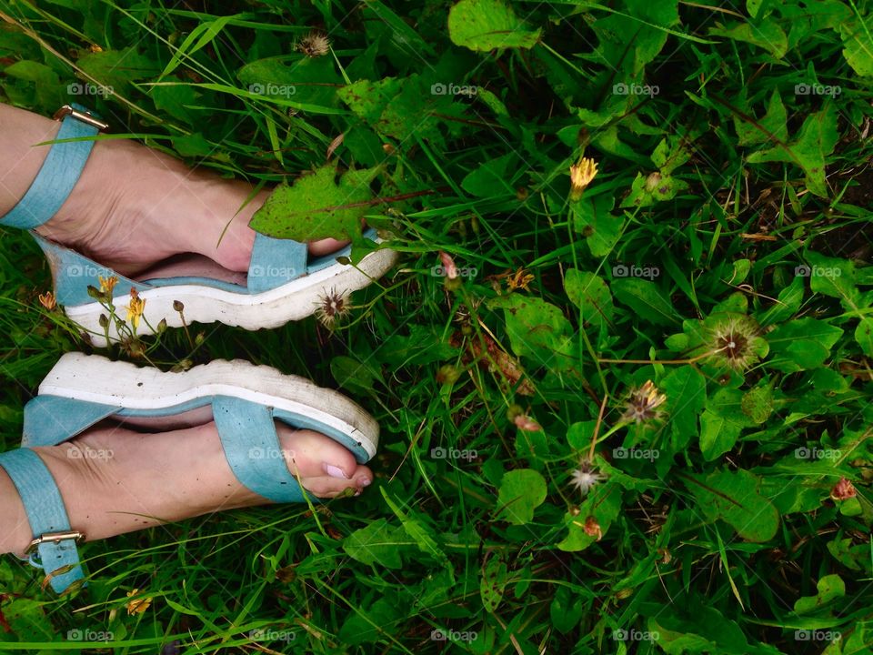 Green sandals in front of grass background. Relaxation after long walk. Comfortable shoes