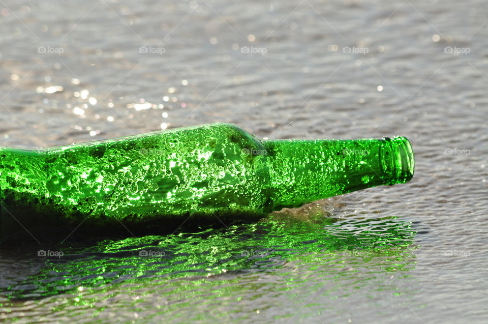 green glass bottle in thed baltic sea water on the beach