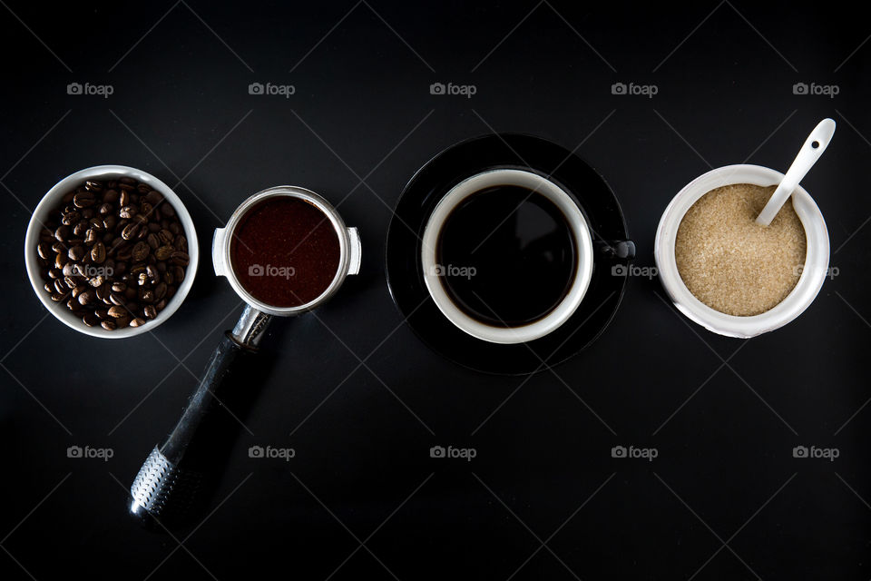 Composition using symmetrical shapes and lines. Coffee scene with beans porta filter cup and sugar. Simple with negative space around image. Flat lay from top.