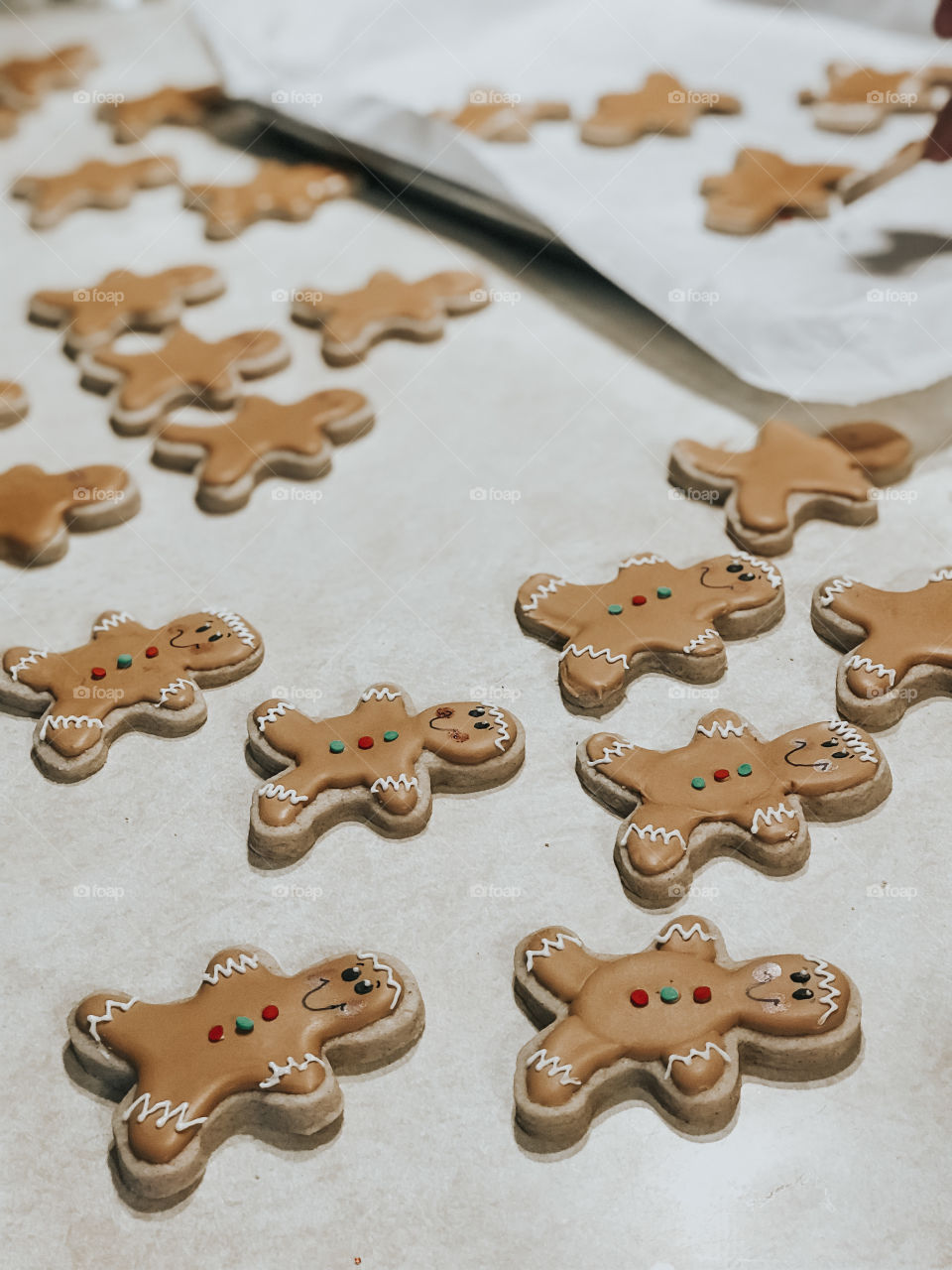 Gingerbread sugar cookies being decorating flat lay on counter and on cookie sheet for Christmas 