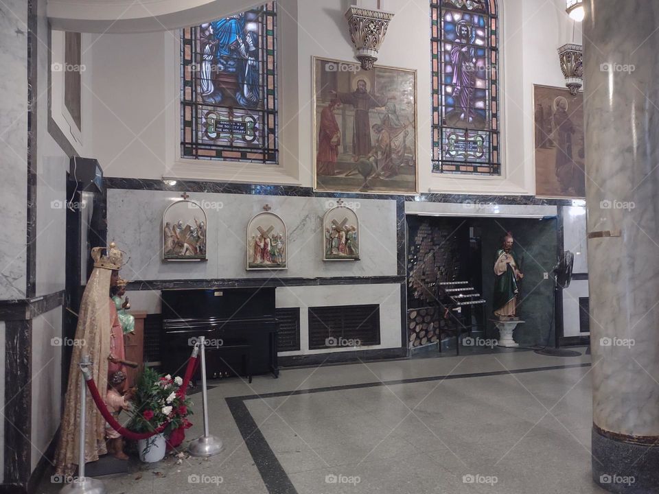 Niche with votive candles, statues, paintings, Stations of the Cross, and Stained Glass windows at the Shrine Church of the Precious Blood in Little Italy, NYC.