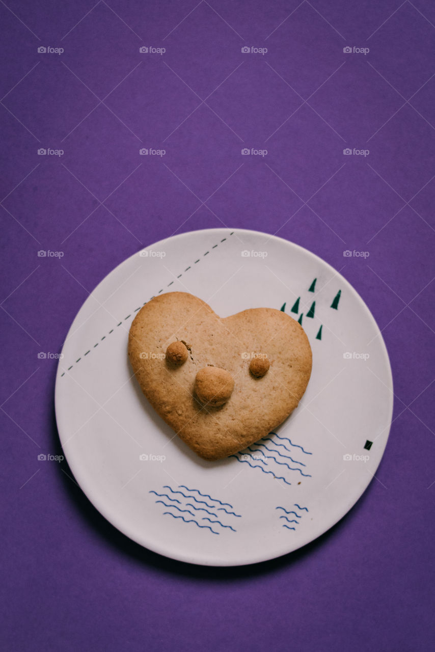 Heart shaped gingerbread cookie on a small plate. Baking with kids, snacks for Santa.