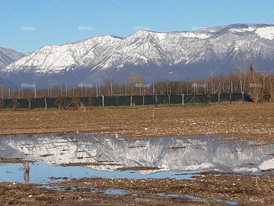 reflection of the mountains covered by snow after some days of rain