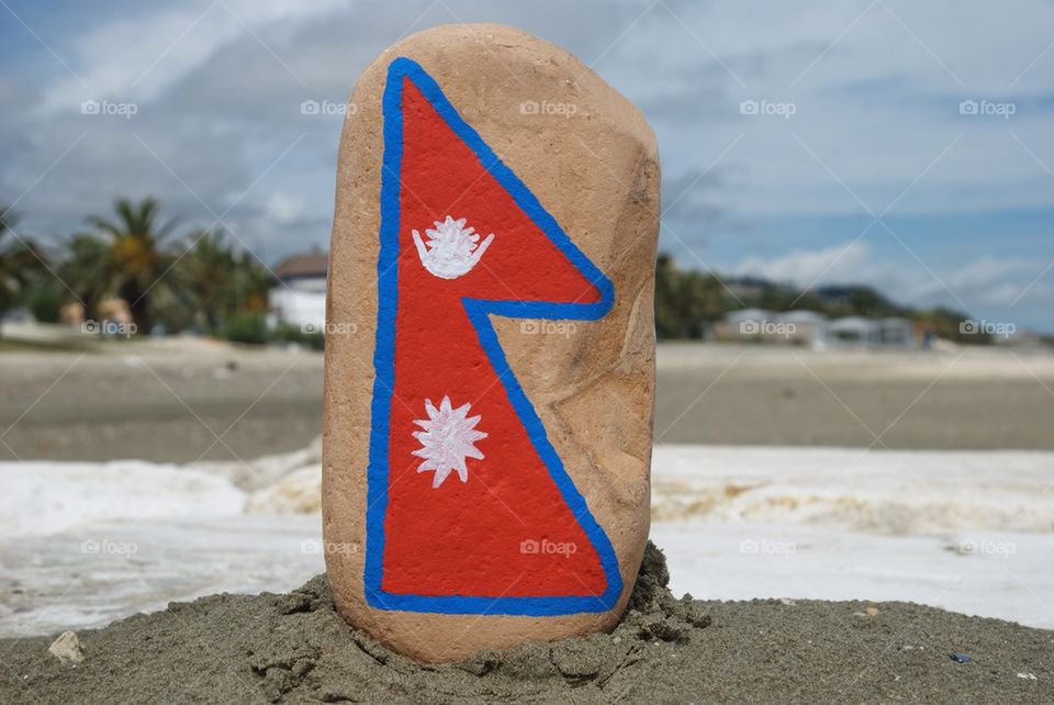 Flag of Nepal on a stone with beach background