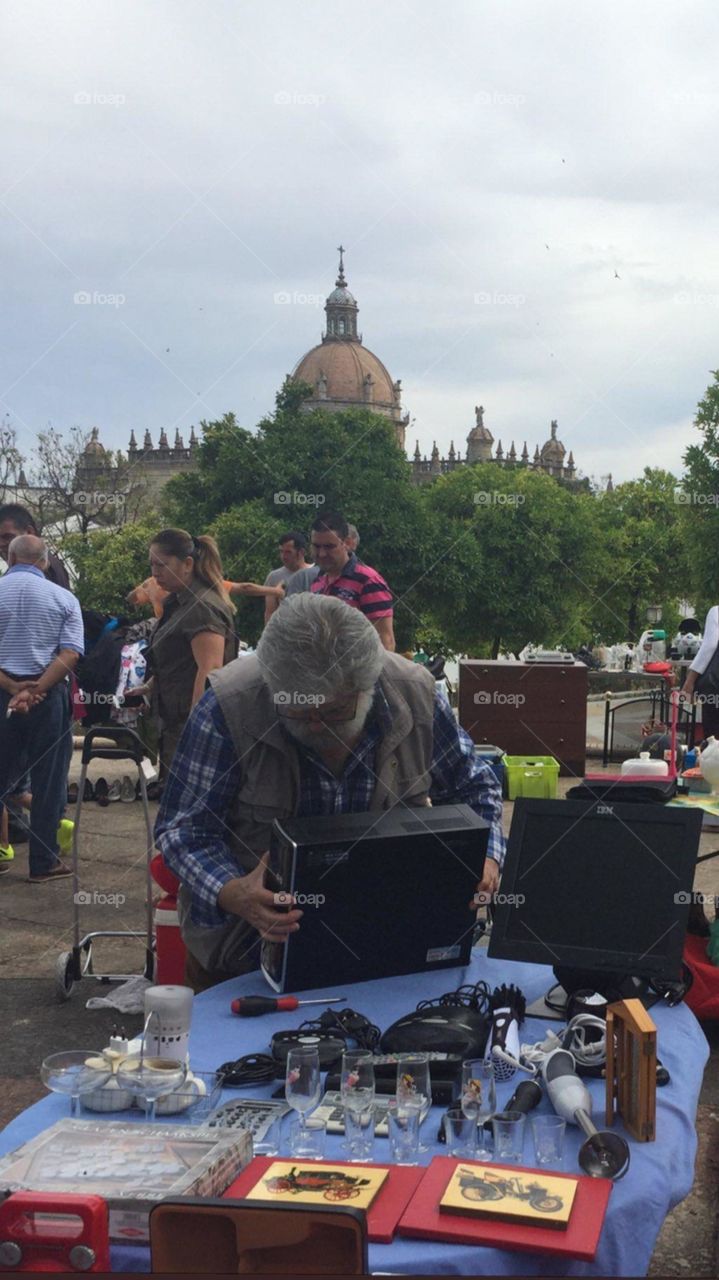 old man checking electronics at jumb sale