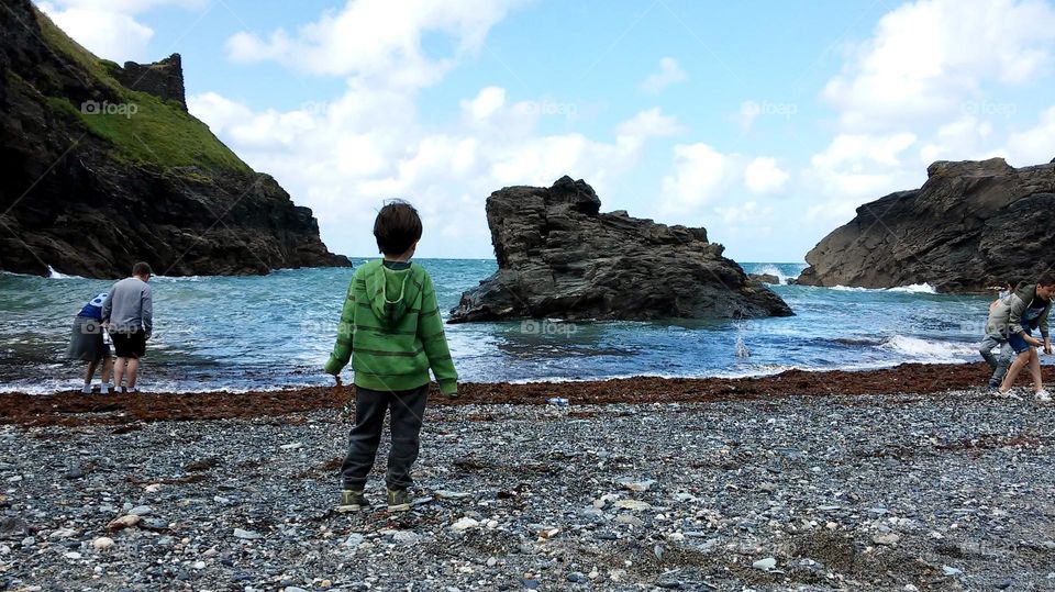 Kid watching the sea at a rocky beach