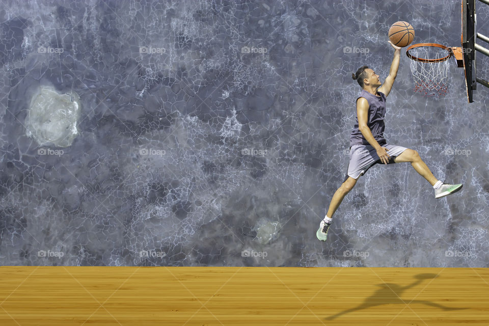 Basketball in hand man jumping Throw a basketball hoop On the wooden floor Background plaster wall loft  with The pattern of cracks.