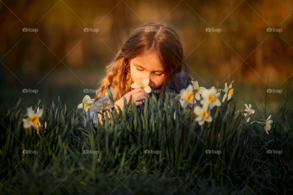 Little girl with narcissus at sunset