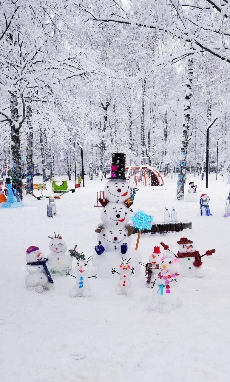 A family of cheerful snowmen from freshly fallen snow in a winter city park