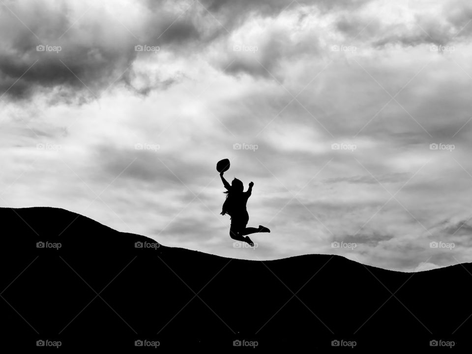 Lady jumping while holding her hat