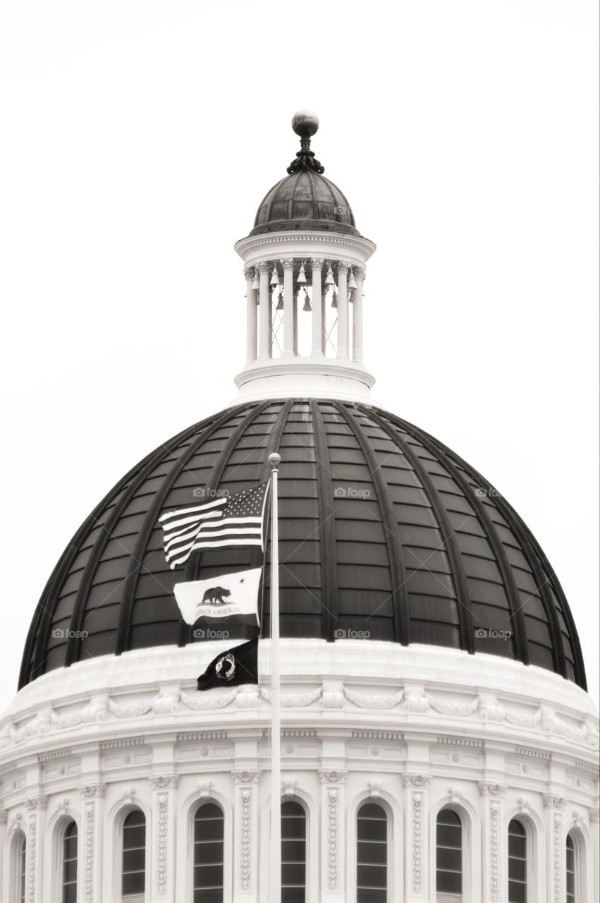 thee black and white flags at the top of a State Building