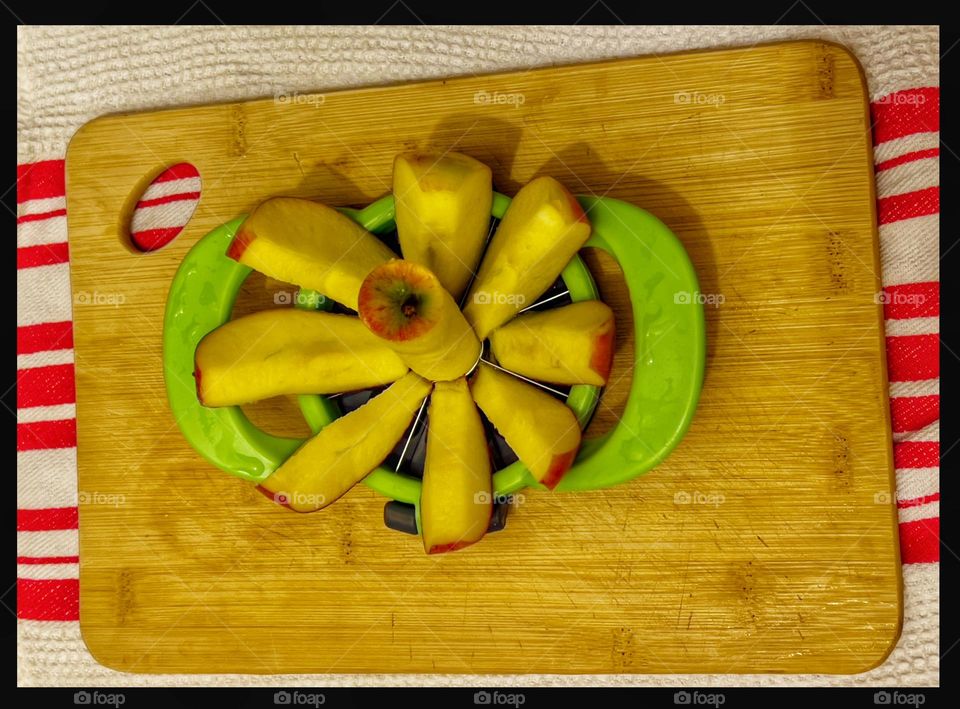 An apple cut into pieces by an apple cutting device.