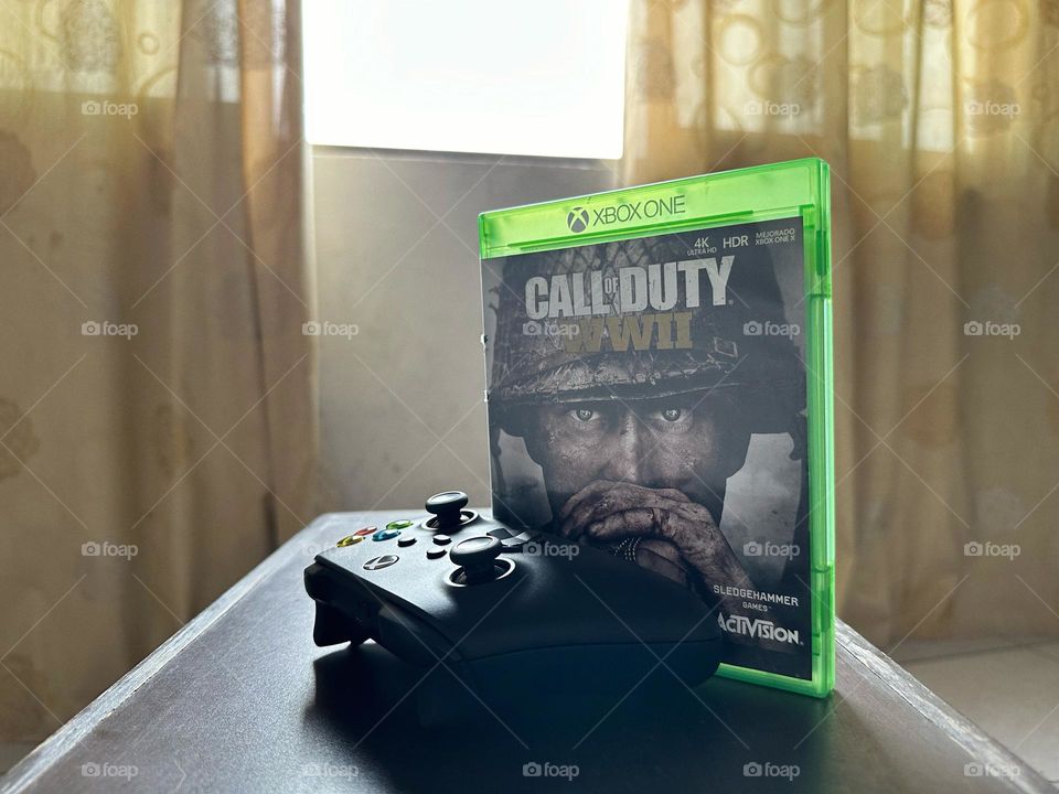 Call of duty video game box behind of a Xbox controller with natural light at the background.