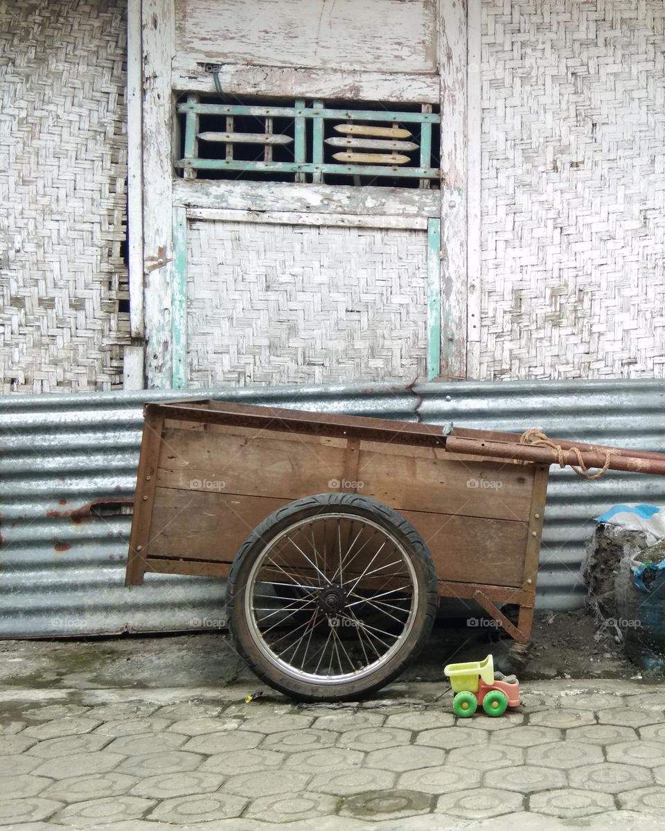 wooden trailer to pick the harvest.  against corrugated iron sheets and old woven bamboo wall of barn