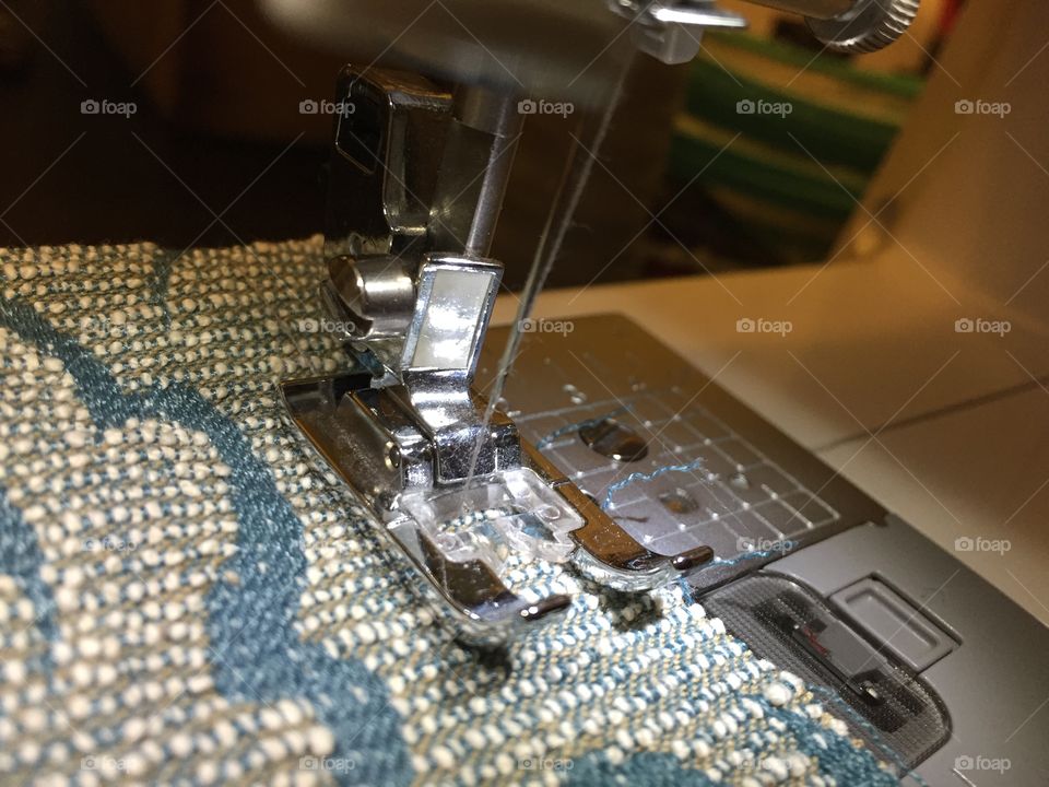 A closeup view of a sewing machine presser foot placed to sew a seam.