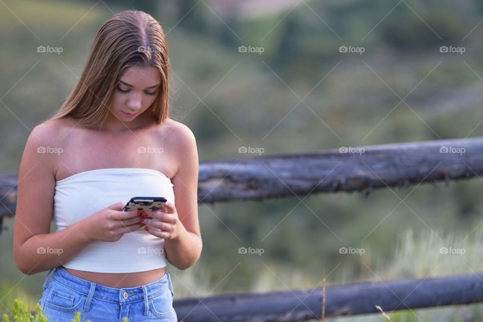 Young woman on cell phone while in the mountains