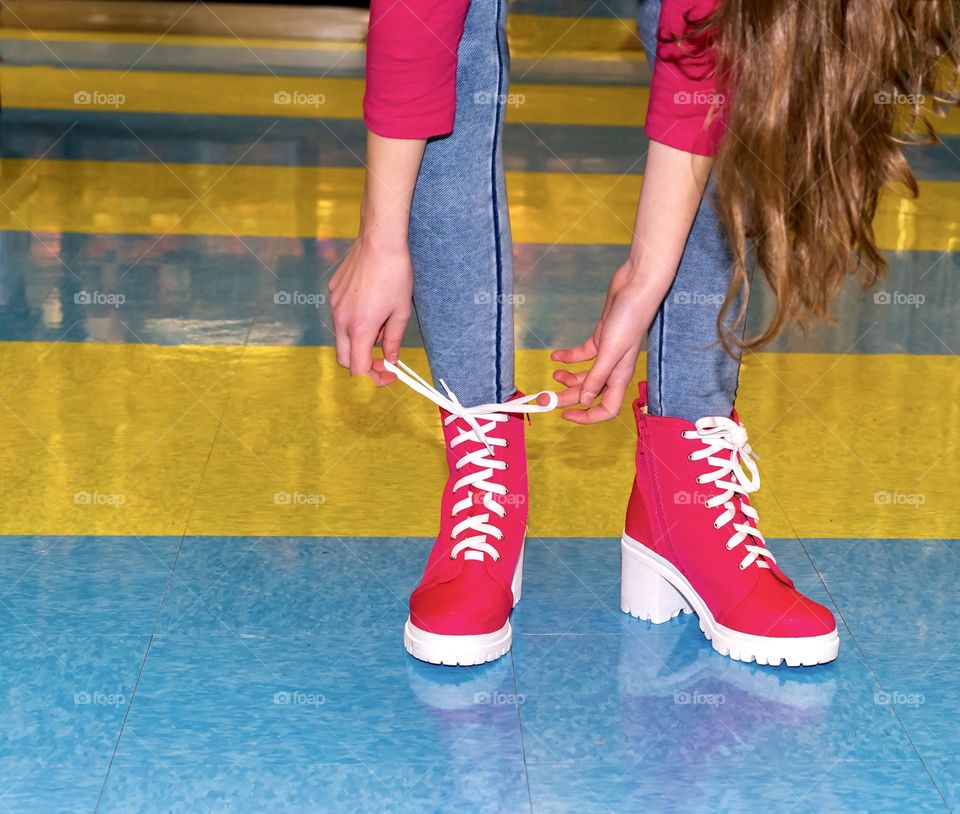 Girl tying bright white shoe laces on hot pink boots