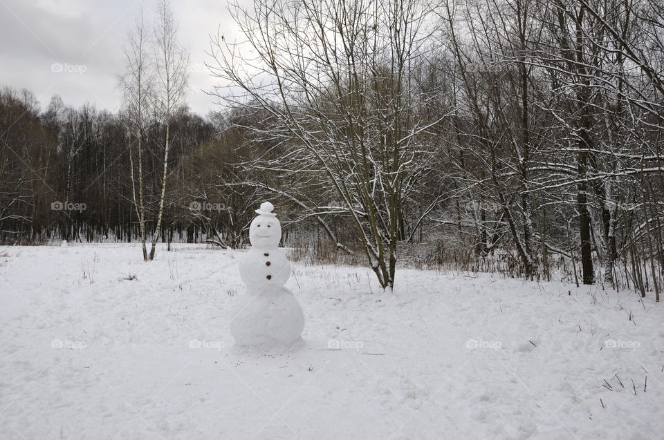 Lonely snowman in the winter forest