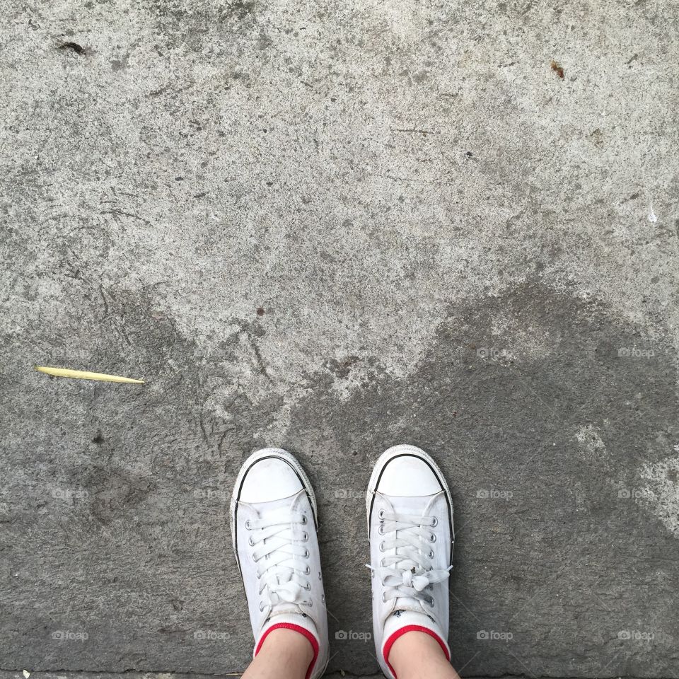 White Sneakers shoes walking on Dirty concrete top view , Canvas shoes walking on concrete great for any use.