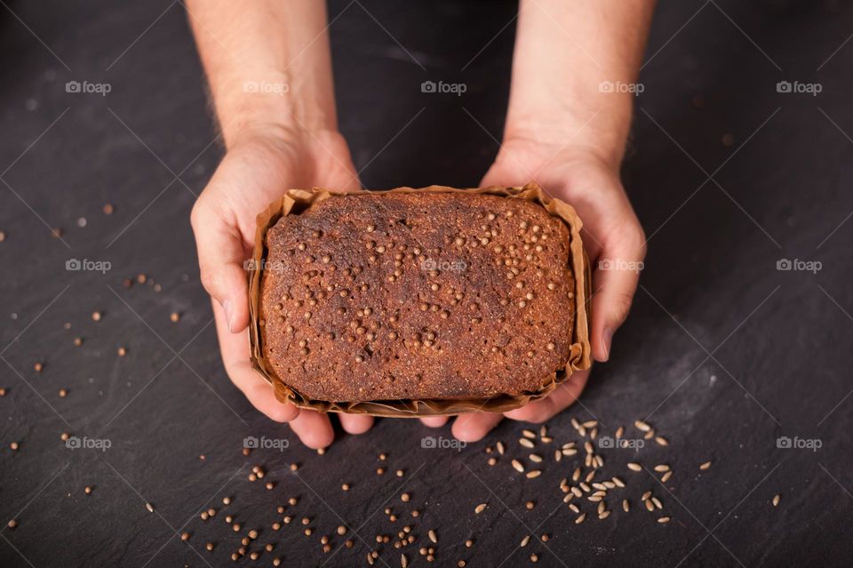 Freshly home baked, wholegrain, rye, brown loaf of bread in wooden baking tray.