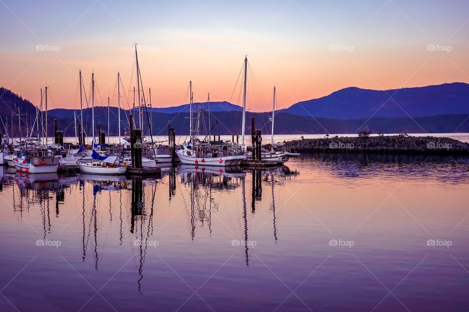 Sailboats on a reflective Pacific Ocean on Cowichan Bay, Canada 