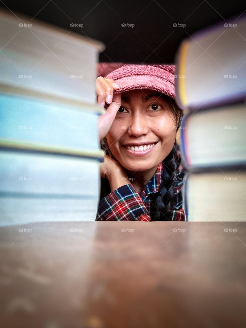 Portrait of a woman wearing a red hat and casual checkered clothing with a smile.