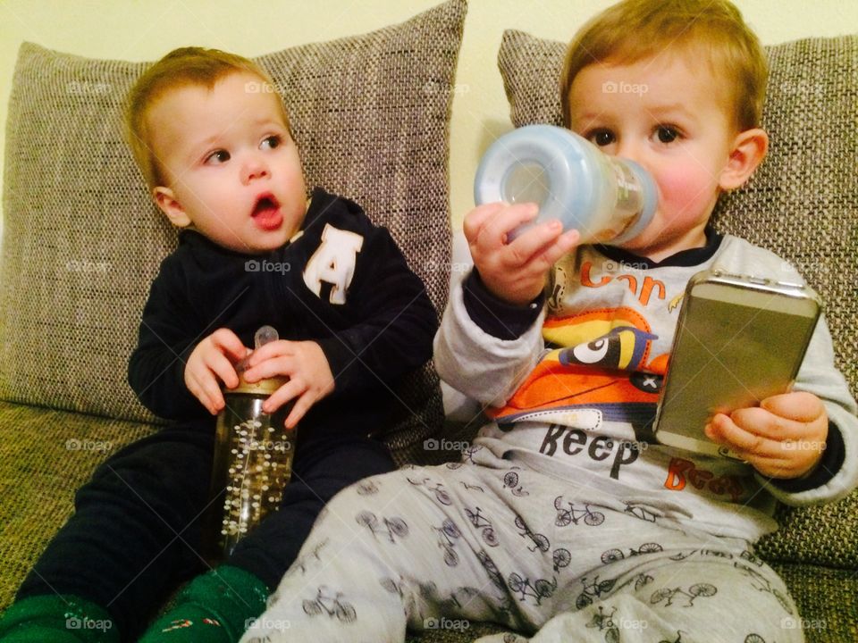 Two cute babies sitting on sofa